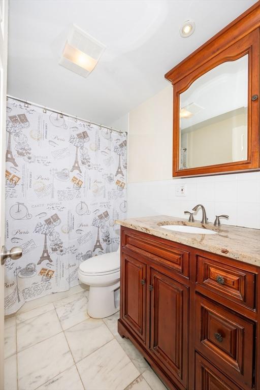 bathroom featuring recessed lighting, toilet, vanity, and marble finish floor