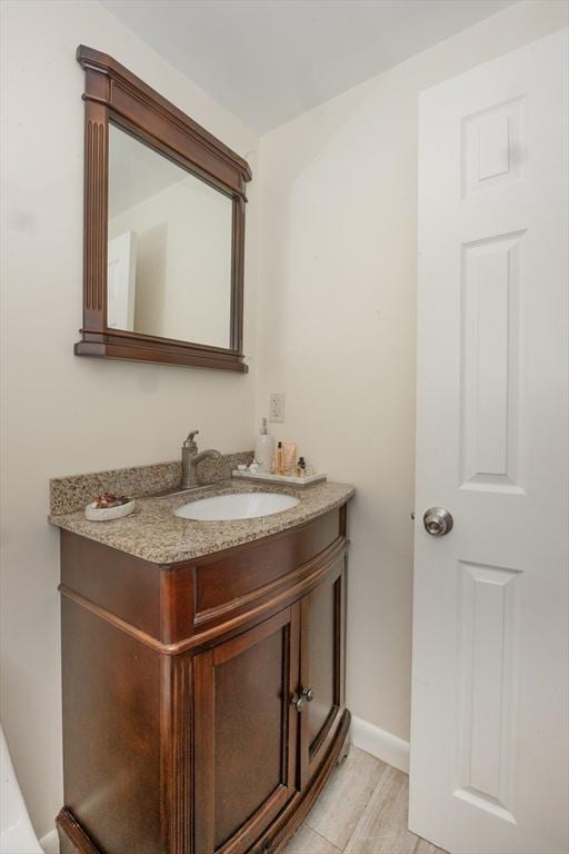 bathroom featuring baseboards, wood finished floors, and vanity
