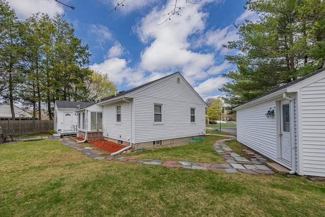 rear view of house with fence, entry steps, and a yard