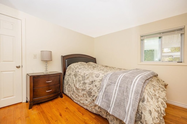 bedroom featuring light wood finished floors and baseboards