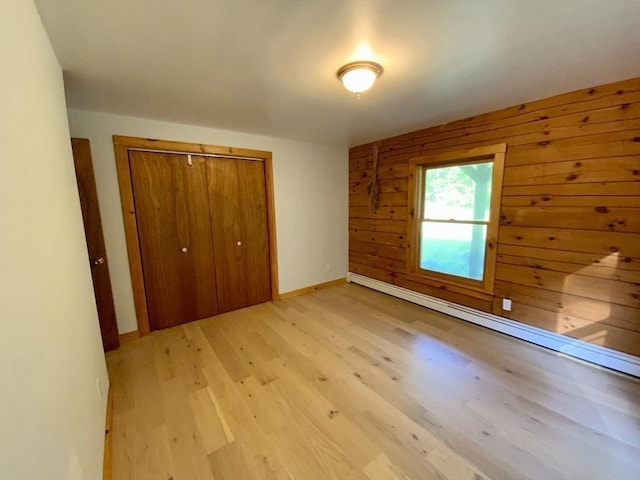 186 Hoosac Rd, Conway, MA 01341 - unfurnished bedroom featuring a closet, light wood-type flooring, a baseboard radiator, baseboards, and wood walls