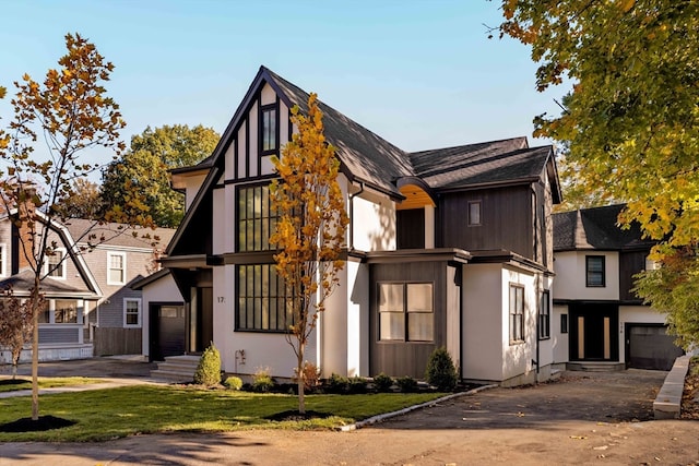 tudor-style house featuring a garage and a front lawn