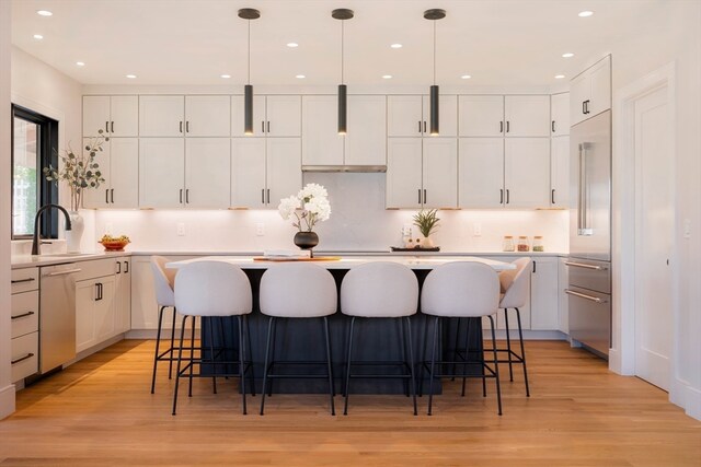 kitchen featuring a kitchen island, white cabinetry, pendant lighting, and sink