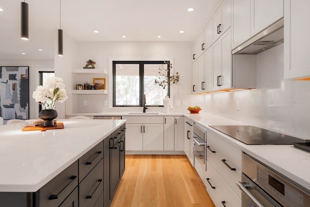 kitchen featuring pendant lighting, black electric cooktop, oven, and white cabinets