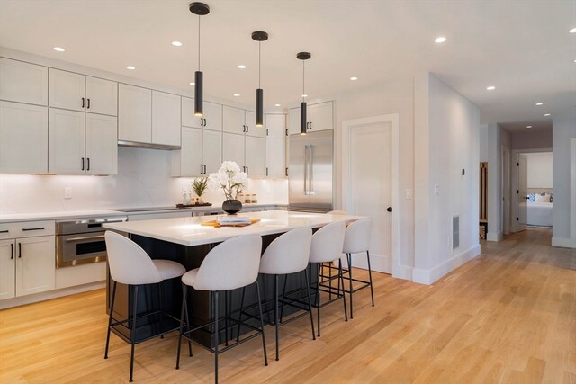 kitchen featuring appliances with stainless steel finishes, decorative light fixtures, light hardwood / wood-style floors, and white cabinets