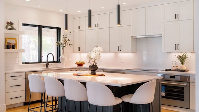 kitchen featuring light hardwood / wood-style floors, stainless steel appliances, a center island, white cabinets, and tasteful backsplash