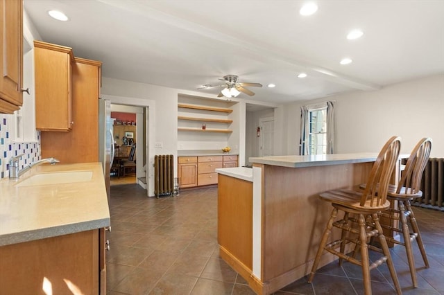 21 College Hill Rd, Somerville, MA 02144 - kitchen with radiator heating unit, a breakfast bar, a sink, recessed lighting, and light countertops