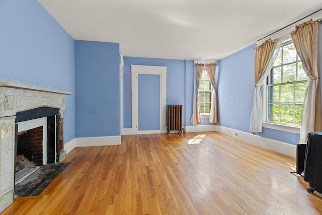 21 College Hill Rd, Somerville, MA 02144 - unfurnished living room featuring radiator, wood finished floors, a fireplace with flush hearth, and plenty of natural light
