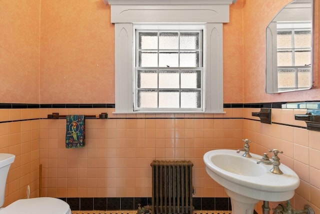 21 College Hill Rd, Somerville, MA 02144 - half bathroom with radiator, toilet, tile walls, wainscoting, and healthy amount of natural light