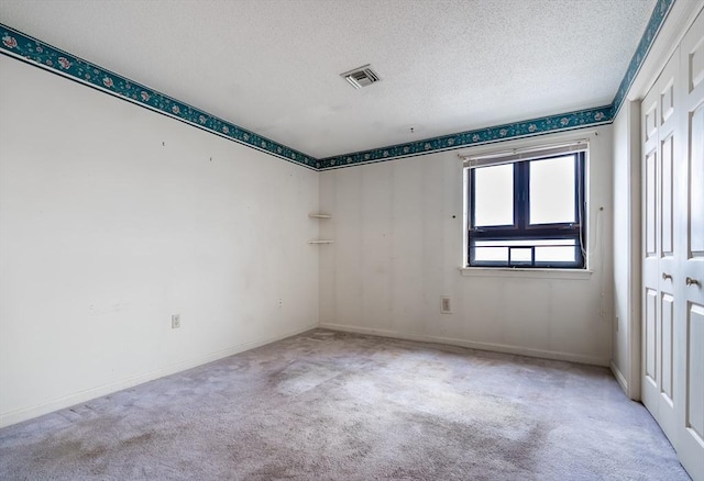 carpeted empty room with a textured ceiling