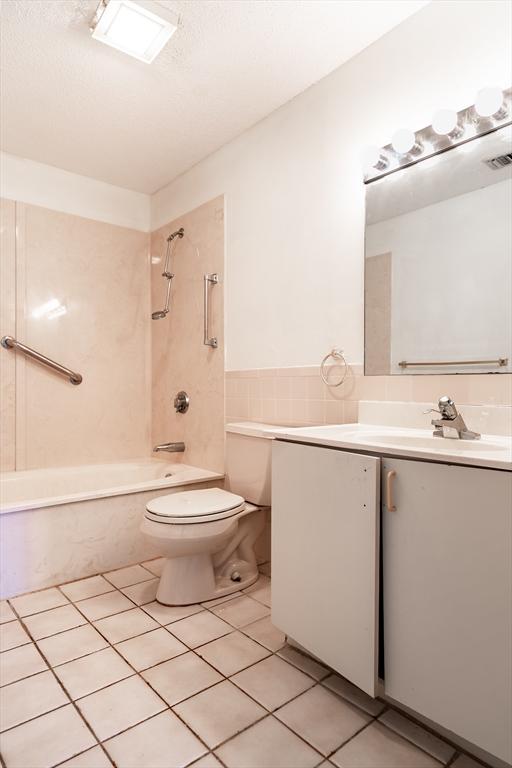 full bathroom with tile patterned floors, toilet, tiled shower / bath combo, and vanity