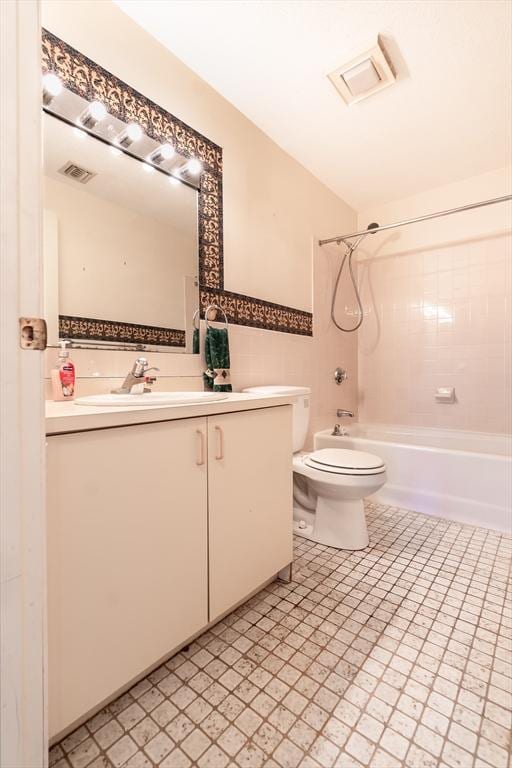 full bathroom featuring vanity, tiled shower / bath combo, and toilet