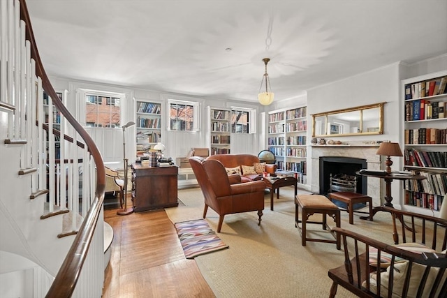 sitting room featuring light wood-type flooring, stairway, built in shelves, and a fireplace