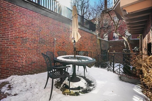 snow covered patio featuring a balcony