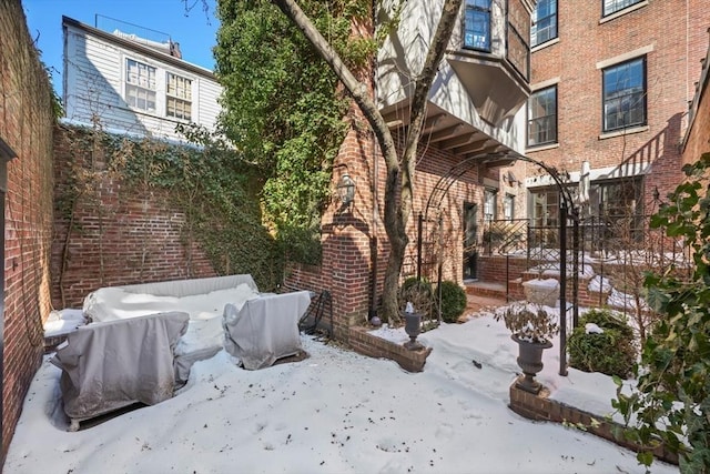 snow covered property featuring brick siding