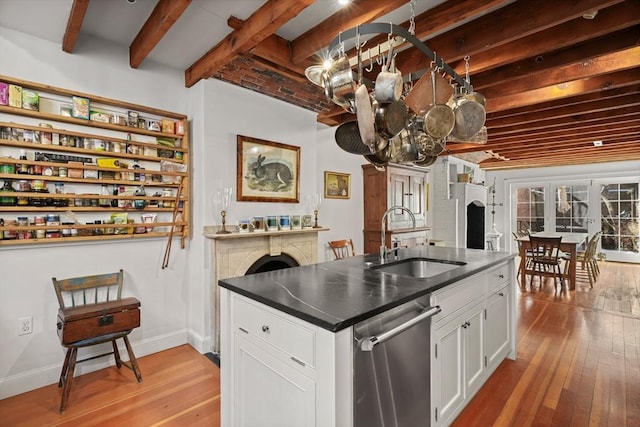 kitchen with a sink, stainless steel dishwasher, a chandelier, light wood-type flooring, and dark countertops