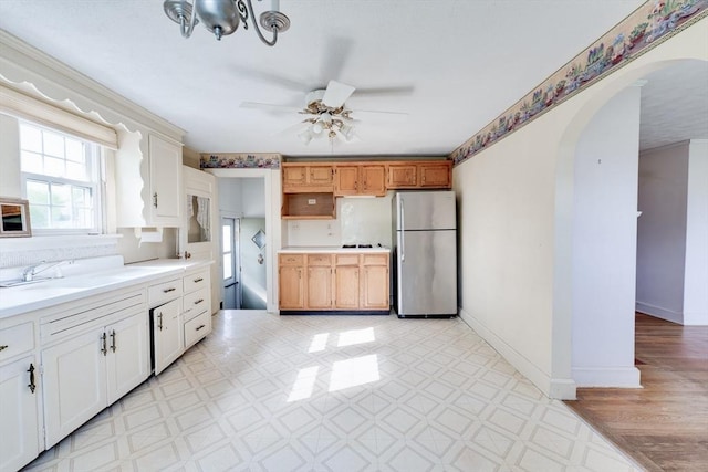 kitchen featuring freestanding refrigerator, arched walkways, ceiling fan, light countertops, and baseboards