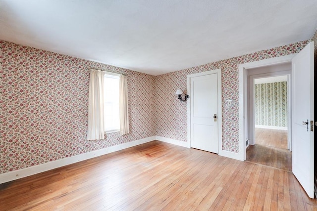 spare room with light wood-style flooring, wallpapered walls, and baseboards