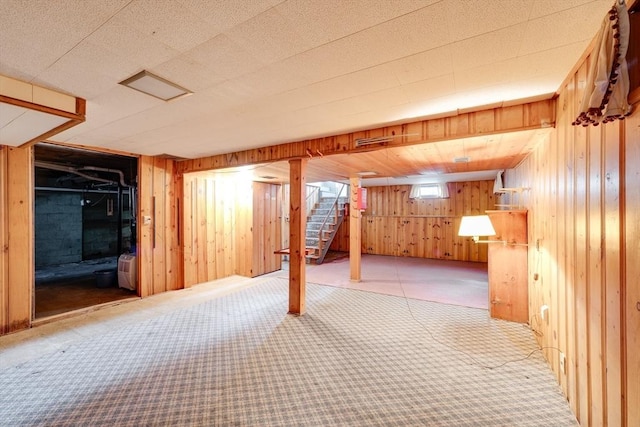 below grade area featuring stairs, carpet floors, and wood walls