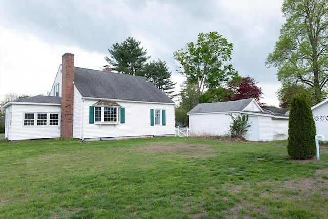 rear view of property with a chimney and a lawn
