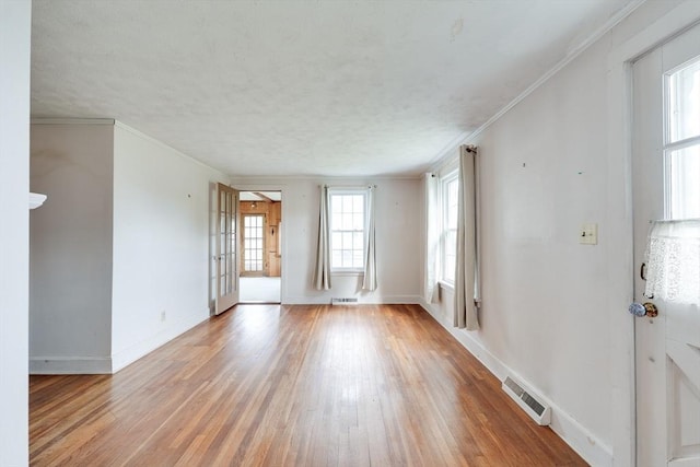 spare room featuring light wood-style flooring, baseboards, and ornamental molding
