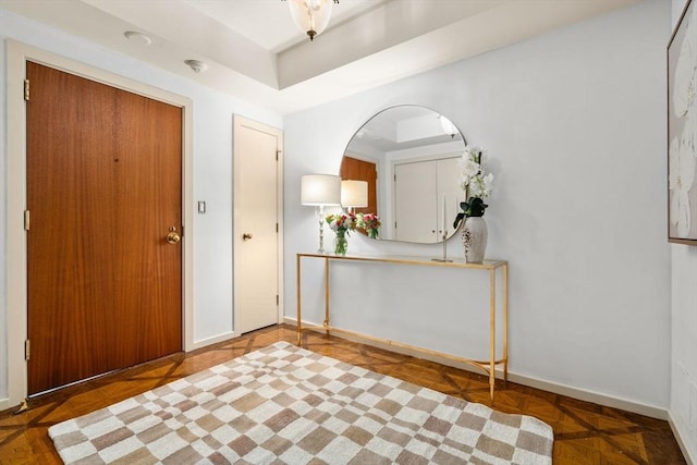 entrance foyer featuring baseboards and a raised ceiling