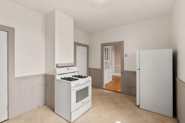57 Rindge Ave, Cambridge, MA 02140 - kitchen with white appliances, wainscoting, light flooring, and wooden walls
