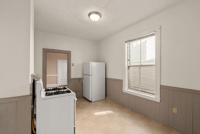 57 Rindge Ave, Cambridge, MA 02140 - kitchen featuring white appliances, a wainscoted wall, light flooring, and wooden walls