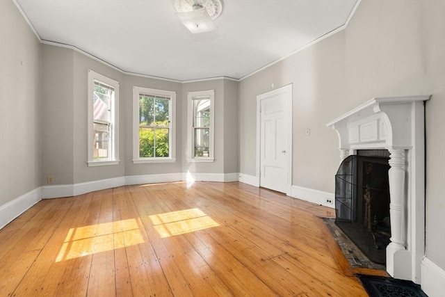 57 Rindge Ave, Cambridge, MA 02140 - unfurnished living room with light wood finished floors, a fireplace with flush hearth, ornamental molding, and baseboards