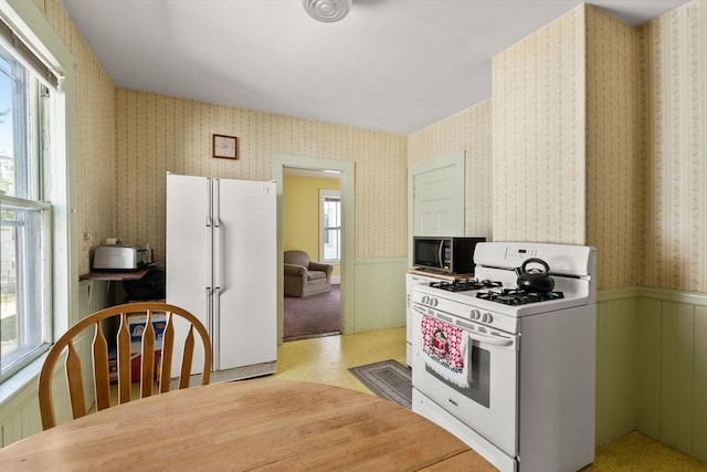 57 Rindge Ave, Cambridge, MA 02140 - kitchen featuring white appliances, a wainscoted wall, and wallpapered walls