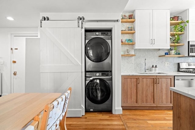 220-224 Washington St Unit 6, Brookline, MA 02445 - laundry area with laundry area, stacked washer / dryer, a barn door, a sink, and light wood finished floors