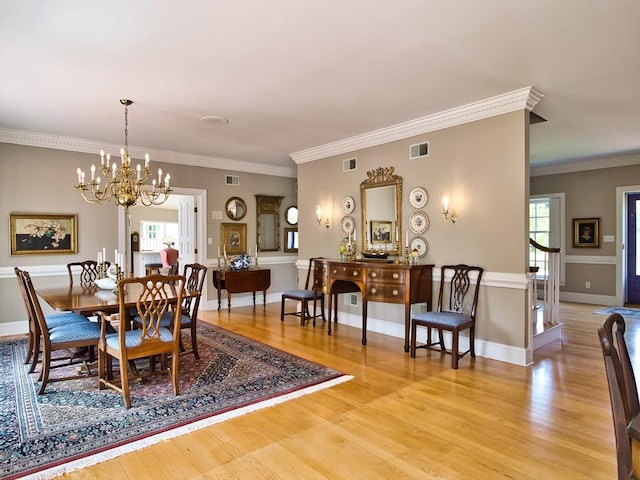 dining room featuring light hardwood / wood-style flooring, ornamental molding, and a notable chandelier