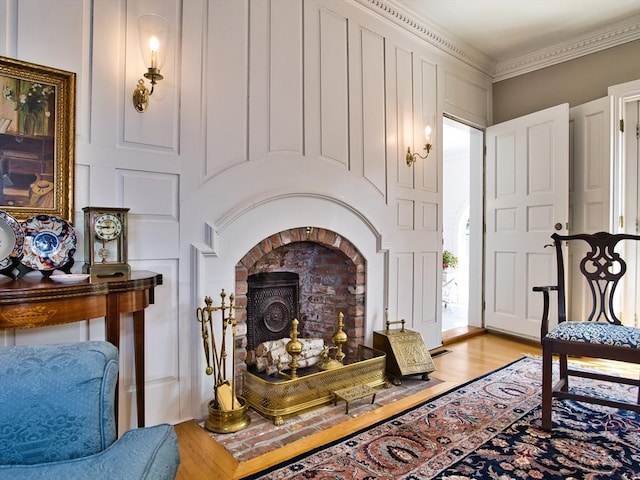 sitting room featuring light wood-type flooring, ornamental molding, and a fireplace