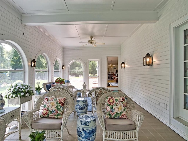 sunroom with ceiling fan and beam ceiling