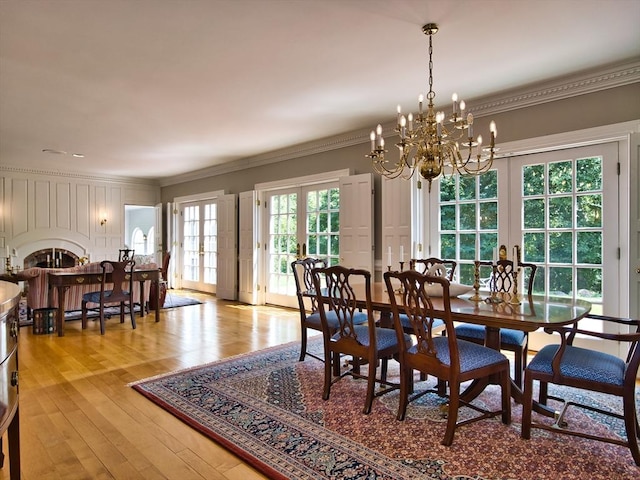 dining area featuring french doors, an inviting chandelier, light hardwood / wood-style floors, and crown molding