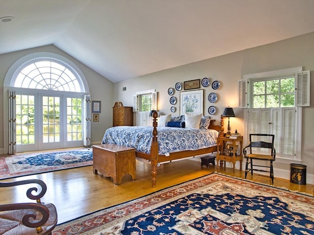 bedroom with hardwood / wood-style floors, multiple windows, and lofted ceiling