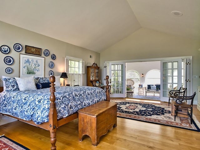 bedroom with light wood-type flooring, vaulted ceiling, and french doors