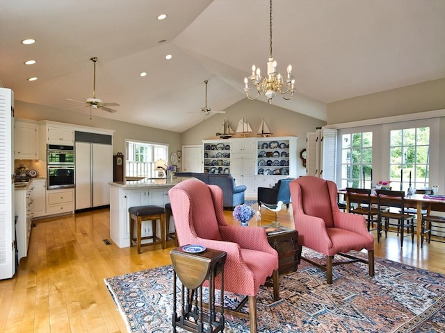 living room featuring ceiling fan, light wood-type flooring, and vaulted ceiling