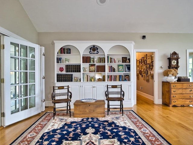 sitting room featuring light wood-type flooring, built in features, and lofted ceiling