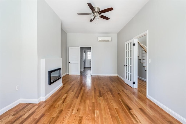 39 Mount Pleasant St, Somerville, MA 02145 - unfurnished living room featuring a glass covered fireplace, light wood finished floors, a wall unit AC, ceiling fan, and stairs