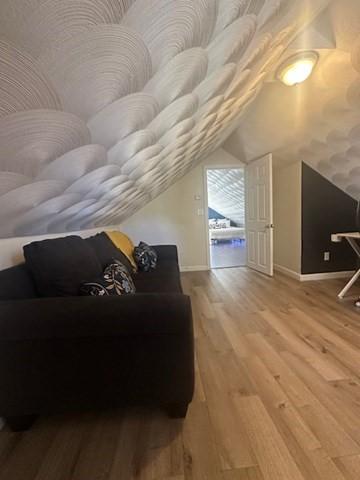 bonus room featuring vaulted ceiling, baseboards, and wood finished floors