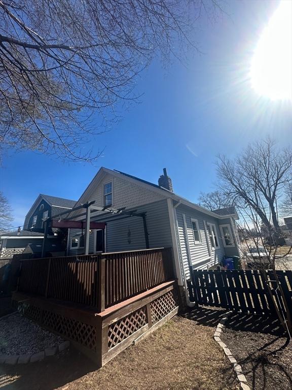 exterior space featuring a wooden deck, a fenced front yard, and a chimney