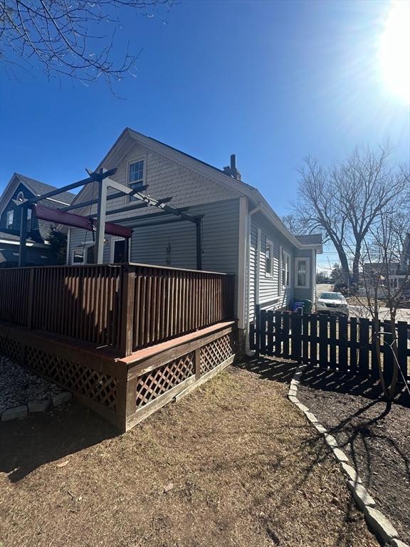 rear view of property with a pergola, a wooden deck, and fence