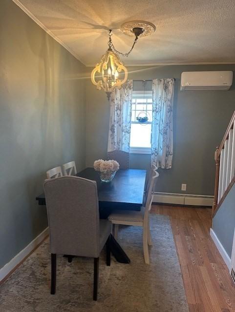 dining area featuring crown molding, stairway, baseboard heating, and a wall mounted AC