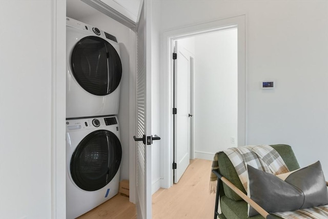 clothes washing area with stacked washing maching and dryer and light hardwood / wood-style flooring