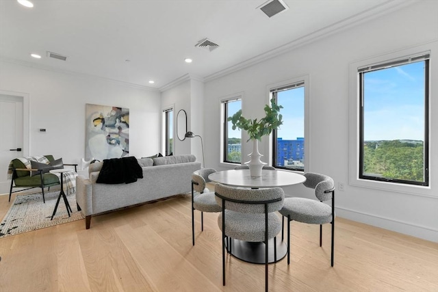 dining room with ornamental molding and light hardwood / wood-style flooring