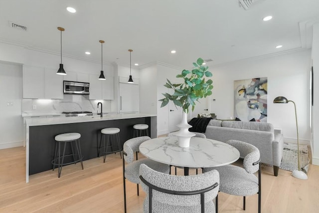 dining room with light hardwood / wood-style floors and crown molding