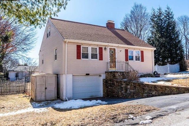 view of front of house featuring a shingled roof, fence, a chimney, and an attached garage