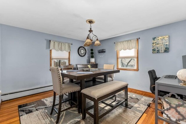 dining area featuring a healthy amount of sunlight, a baseboard heating unit, and wood finished floors