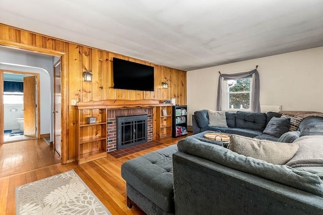 living room featuring hardwood / wood-style flooring, a brick fireplace, and wood walls